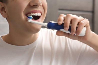 Photo of Man brushing his teeth with electric toothbrush indoors, closeup
