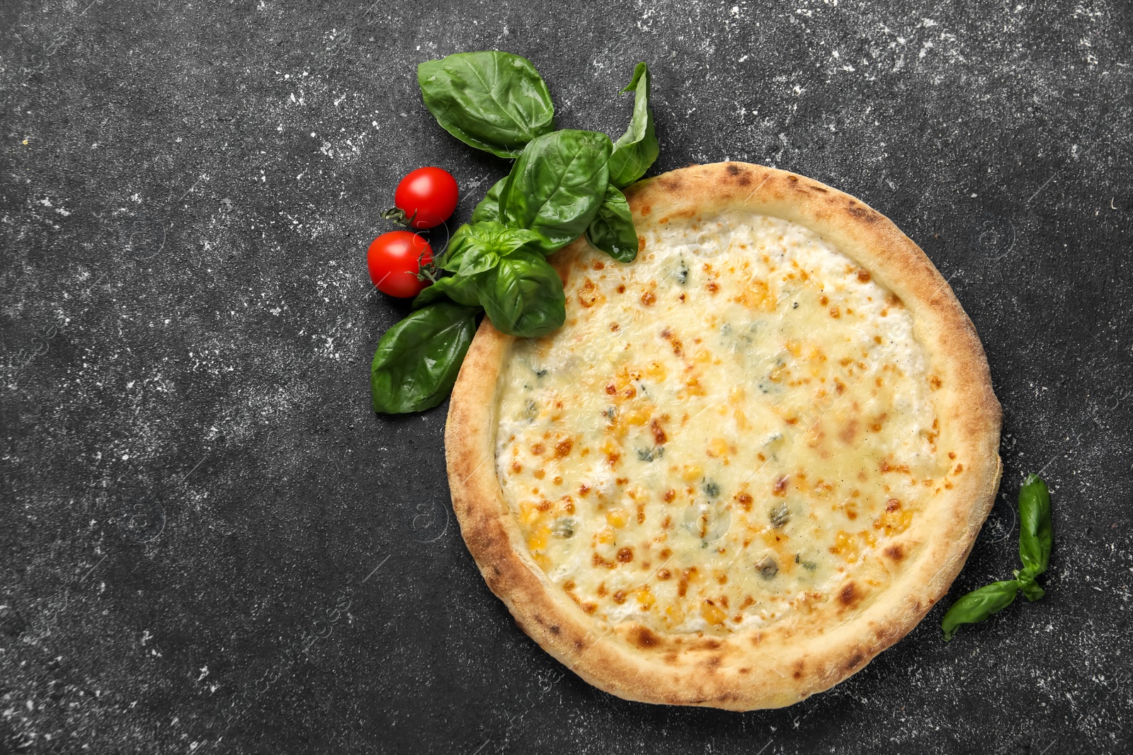 Photo of Delicious cheese pizza, basil and tomatoes on black textured table, flat lay. Space for text