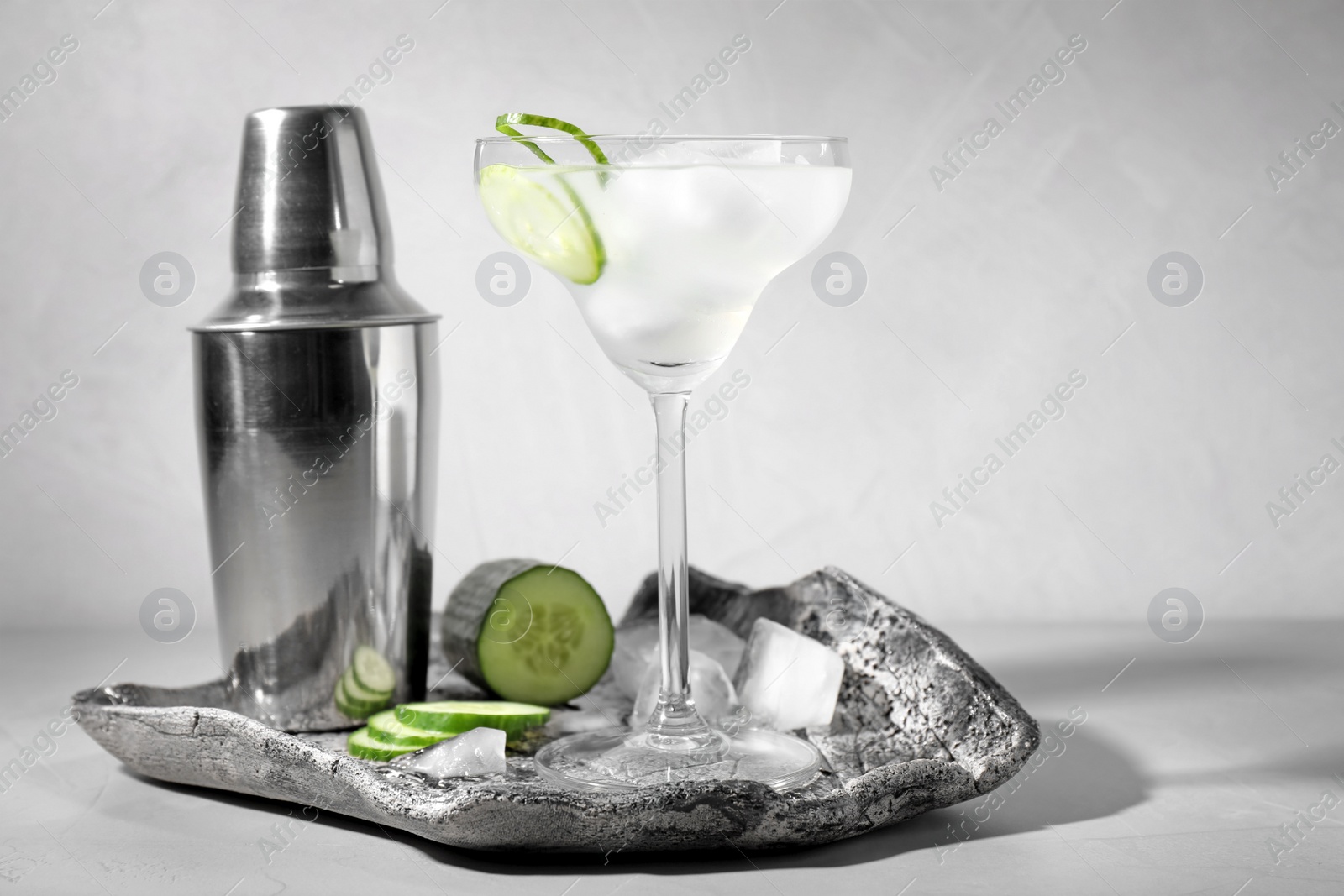 Photo of Composition with glass of cucumber martini on table against light background. Space for text