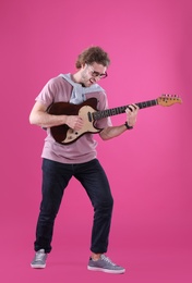 Young man playing electric guitar on color background