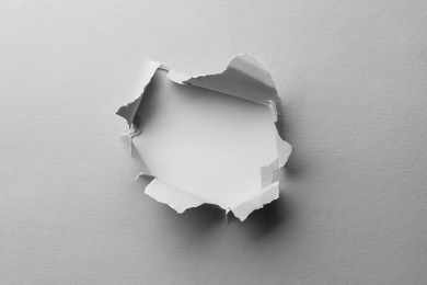 Photo of Hole in white paper on light background