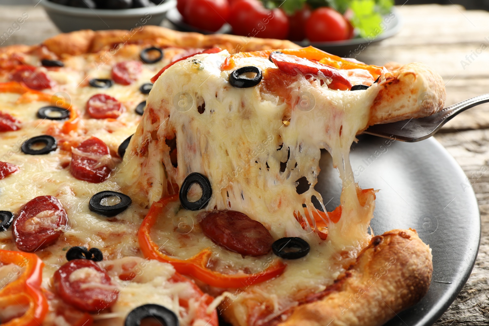 Photo of Taking piece of tasty pizza at table, closeup