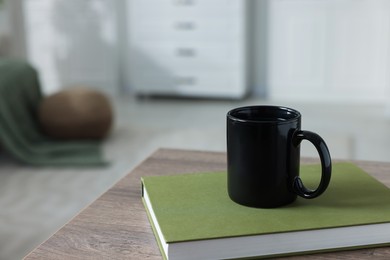 Photo of Ceramic mug of tea and book on wooden table. Mockup for design