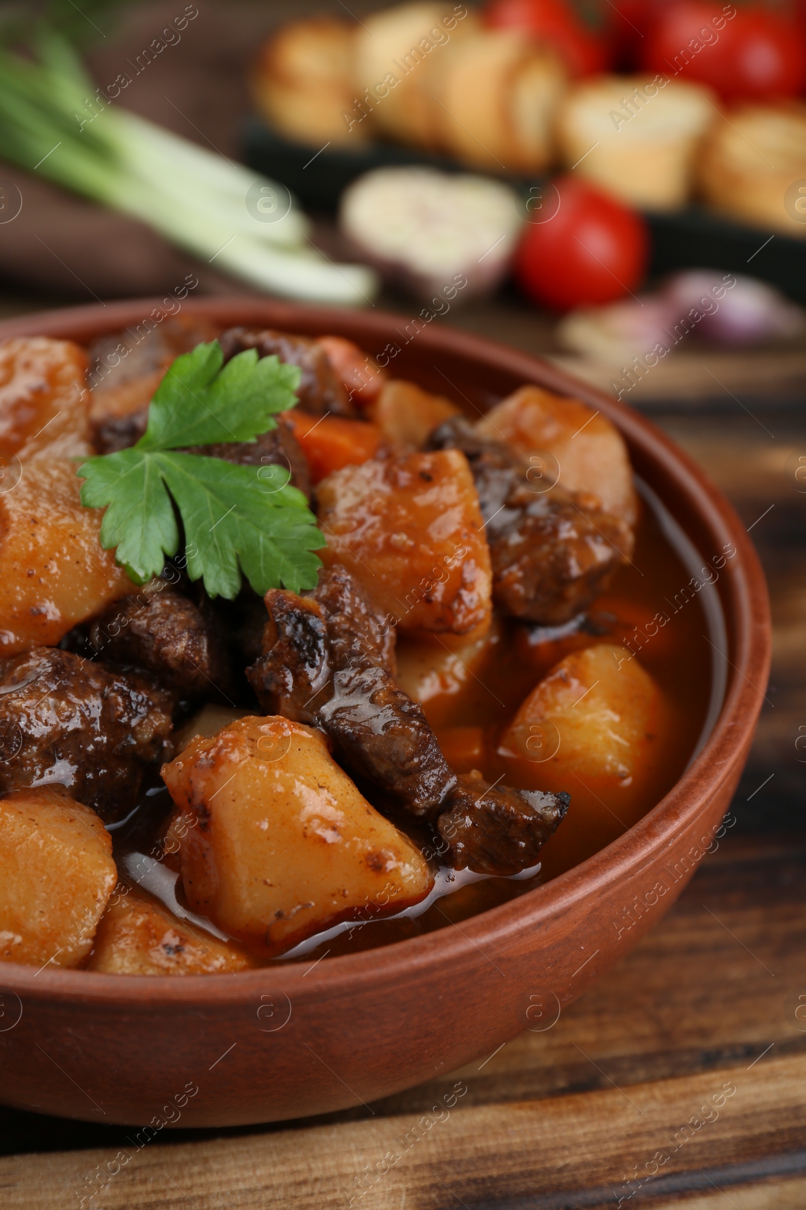 Photo of Delicious beef stew with carrots, parsley and potatoes, closeup