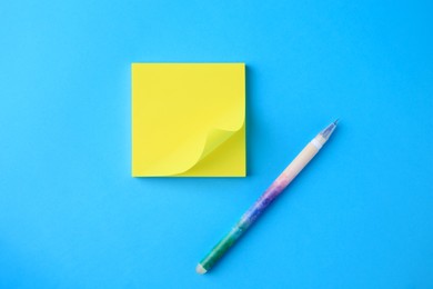 Blank paper note and pen on light blue background, flat lay