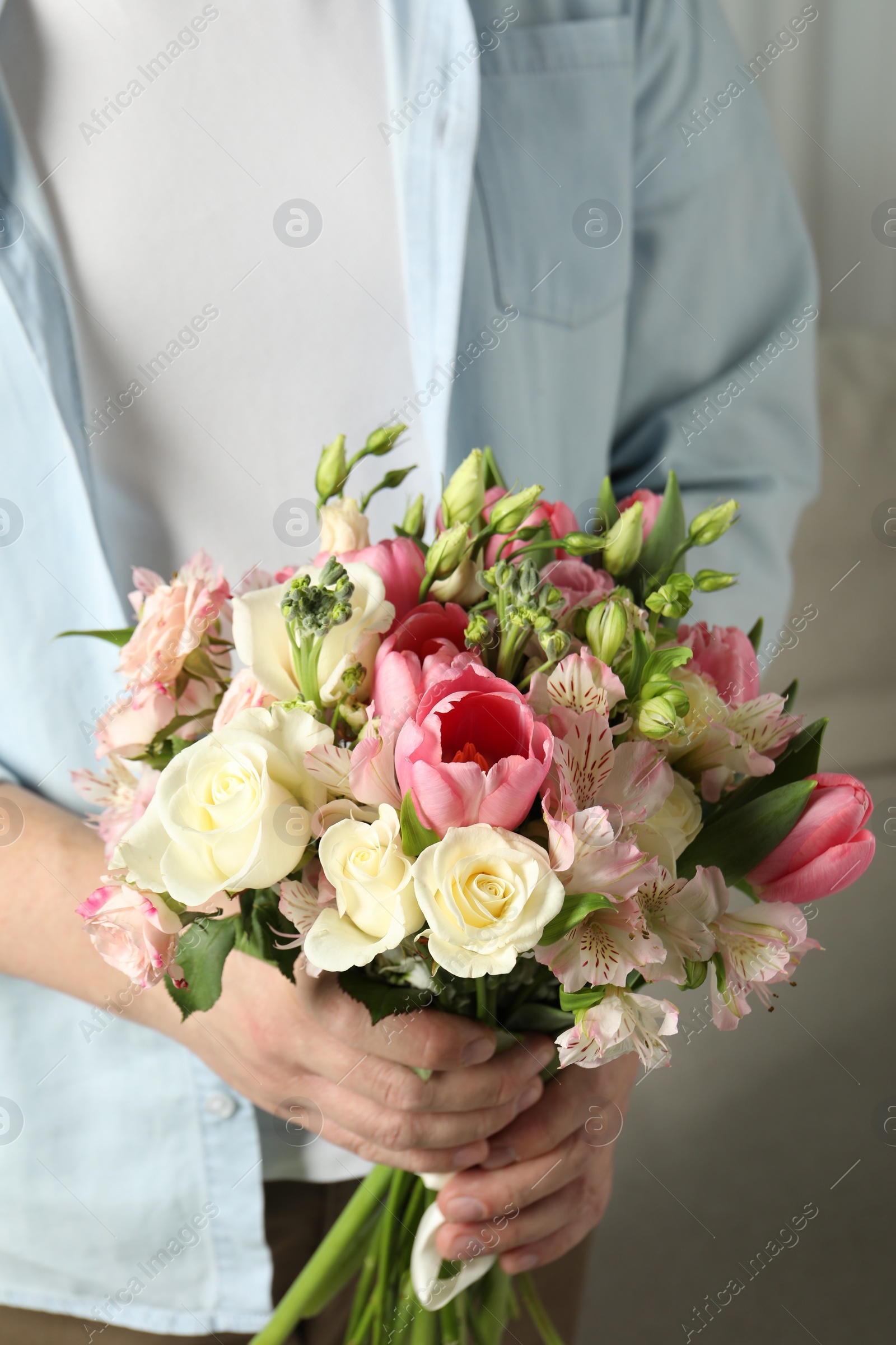 Photo of Man holding bouquet of beautiful flowers indoors, closeup