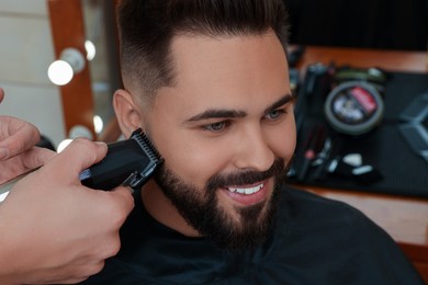 Photo of Professional hairdresser working with client in barbershop, closeup