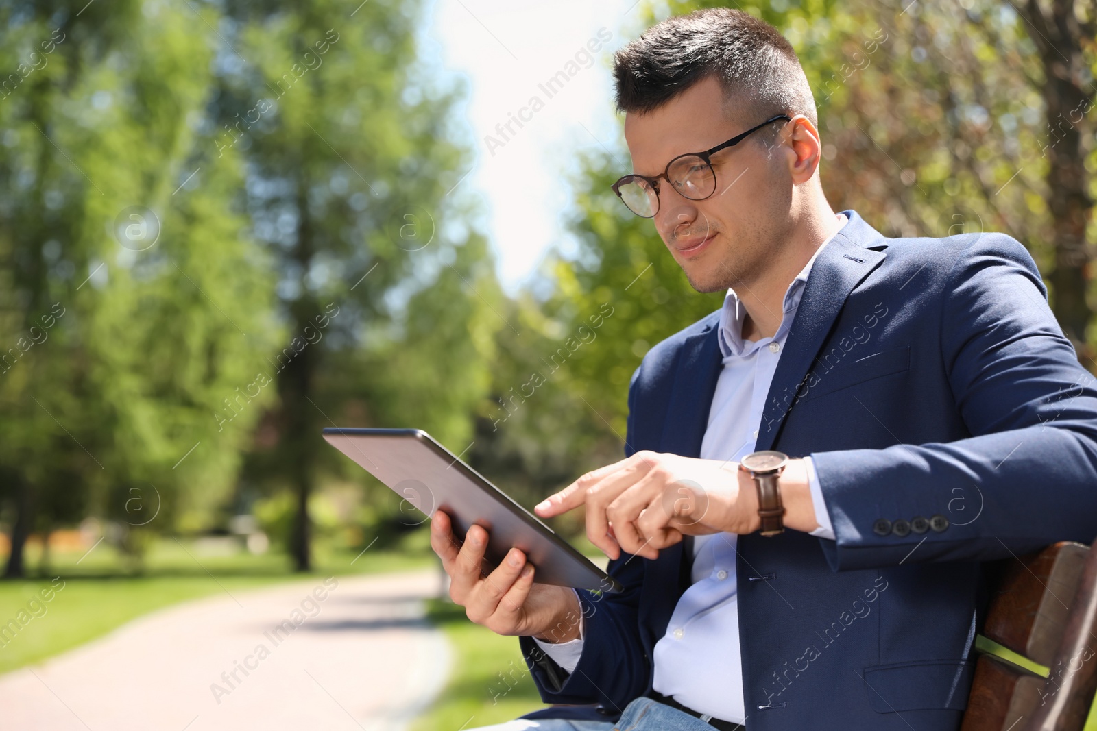 Photo of Man working with tablet on bench in park