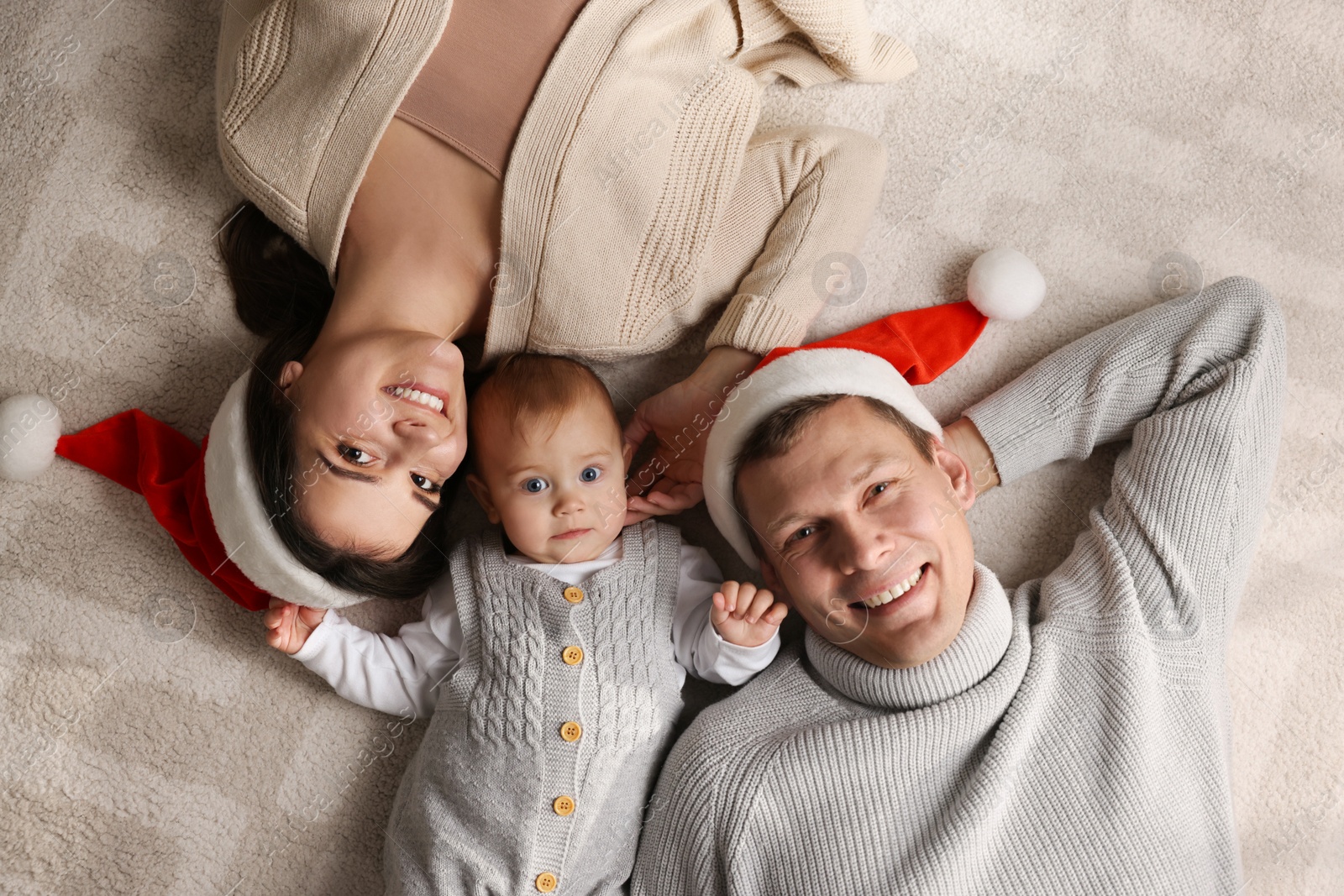 Photo of Happy couple with cute baby on floor, top view. Christmas celebration