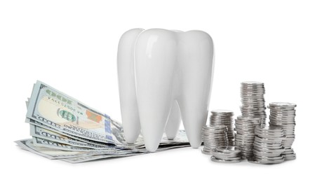 Photo of Ceramic model of tooth, dollar banknotes and coins on white background. Expensive treatment