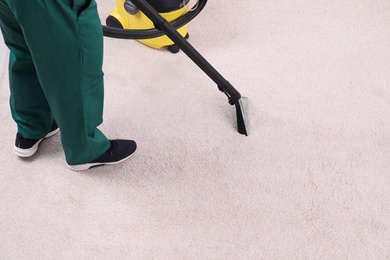 Photo of Man cleaning carpet with vacuum cleaner, closeup. Space for text