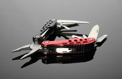Photo of Modern compact portable multitool on grey table