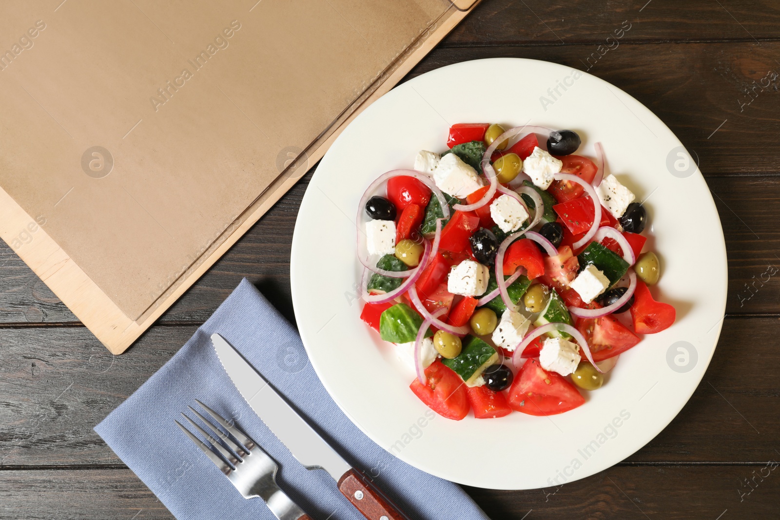 Photo of Plate with delicious salad and menu on table, top view