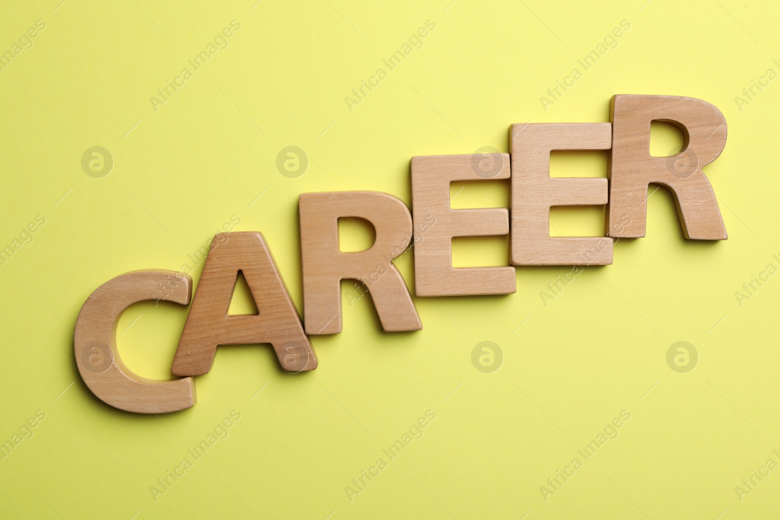 Photo of Word CAREER made with wooden letters on yellow background, flat lay