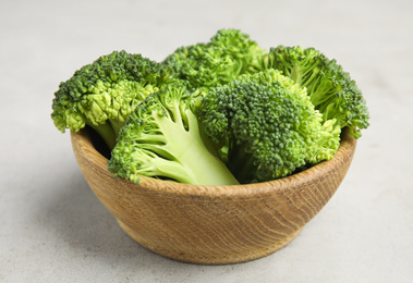 Photo of Fresh green broccoli in wooden bowl on light table, closeup