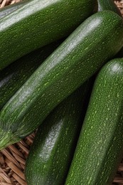 Photo of Raw ripe zucchinis on wicker mat, closeup