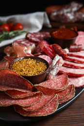 Different types of sausages with mustard served on wooden table, closeup