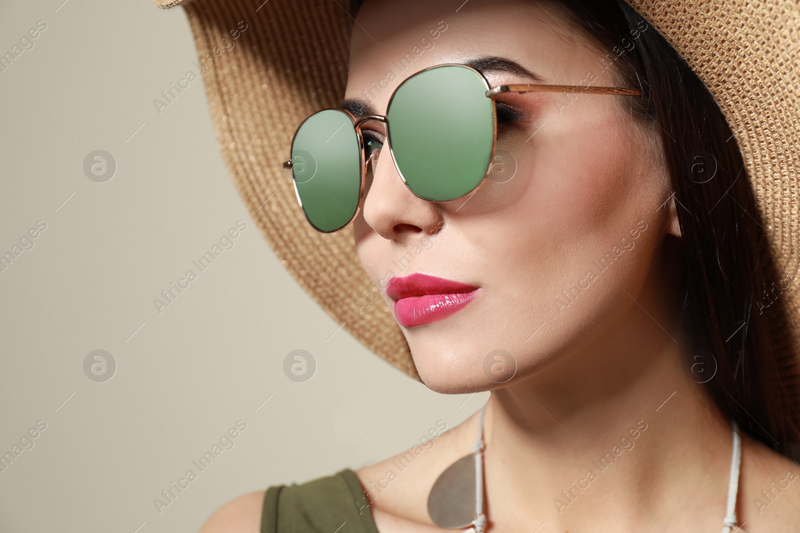 Photo of Beautiful woman in stylish sunglasses and hat on beige background