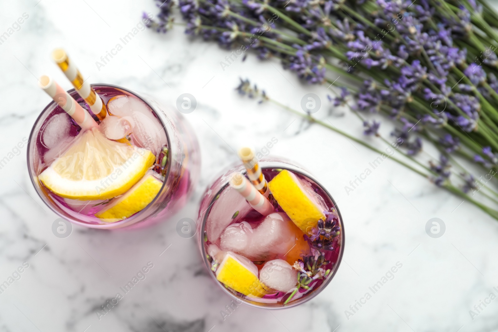 Photo of Fresh delicious lemonade with lavender and straws on white marble table, top view