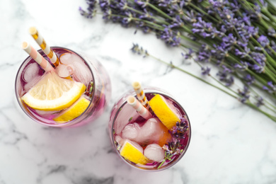 Photo of Fresh delicious lemonade with lavender and straws on white marble table, top view