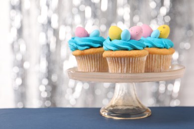 Tasty decorated Easter cupcakes on blue table, closeup