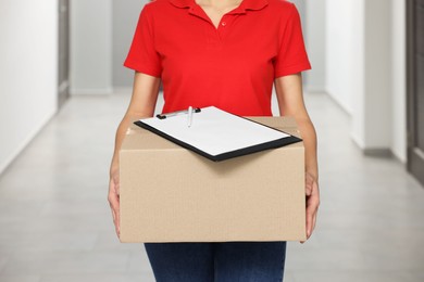 Courier with cardboard box and clipboard in hallway, closeup