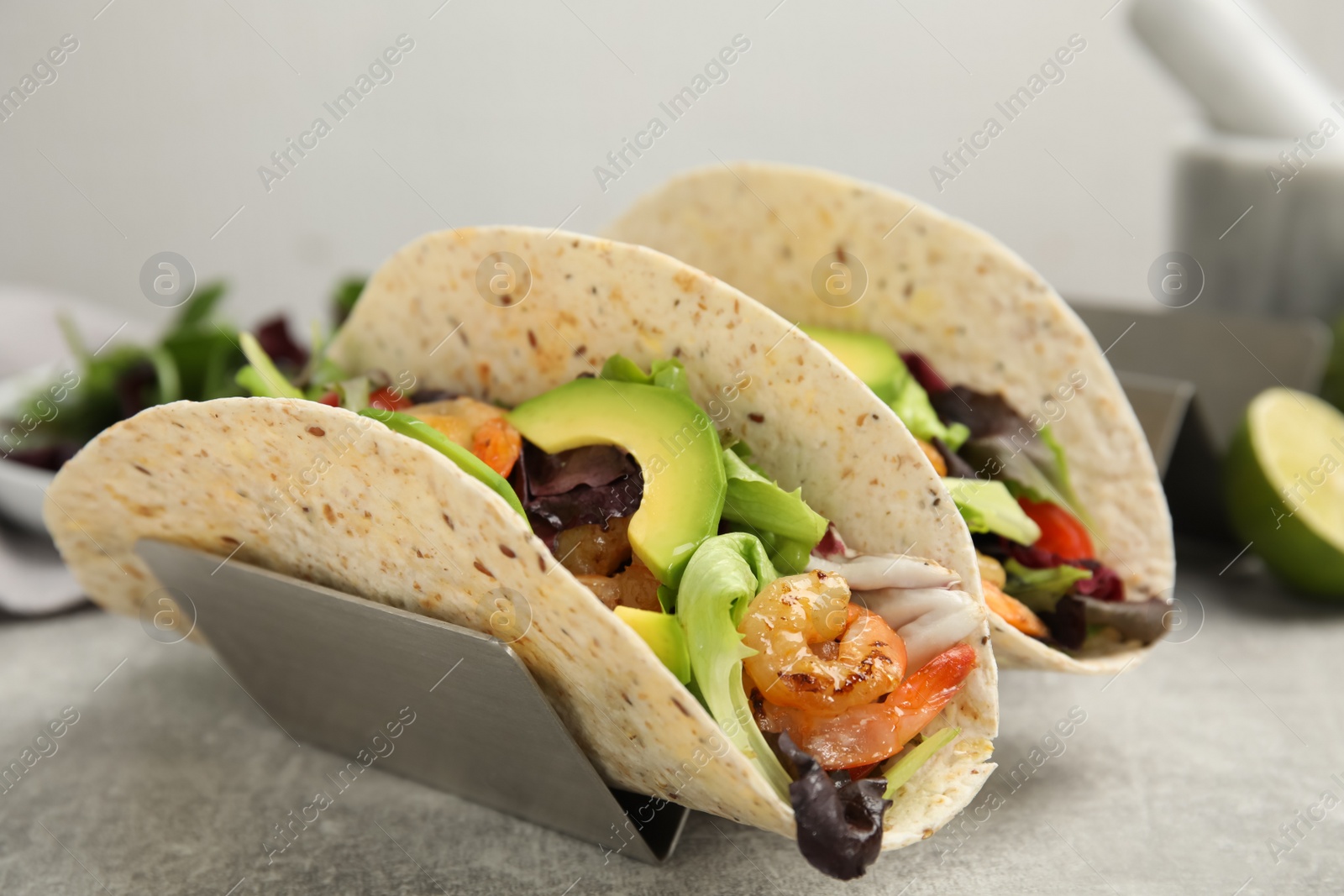 Photo of Delicious tacos with shrimps and avocado on light grey table, closeup