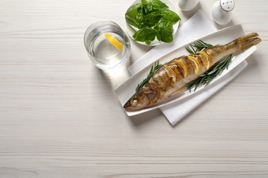 Photo of Tasty homemade roasted pike perch served on white wooden table, flat lay and space for text. River fish