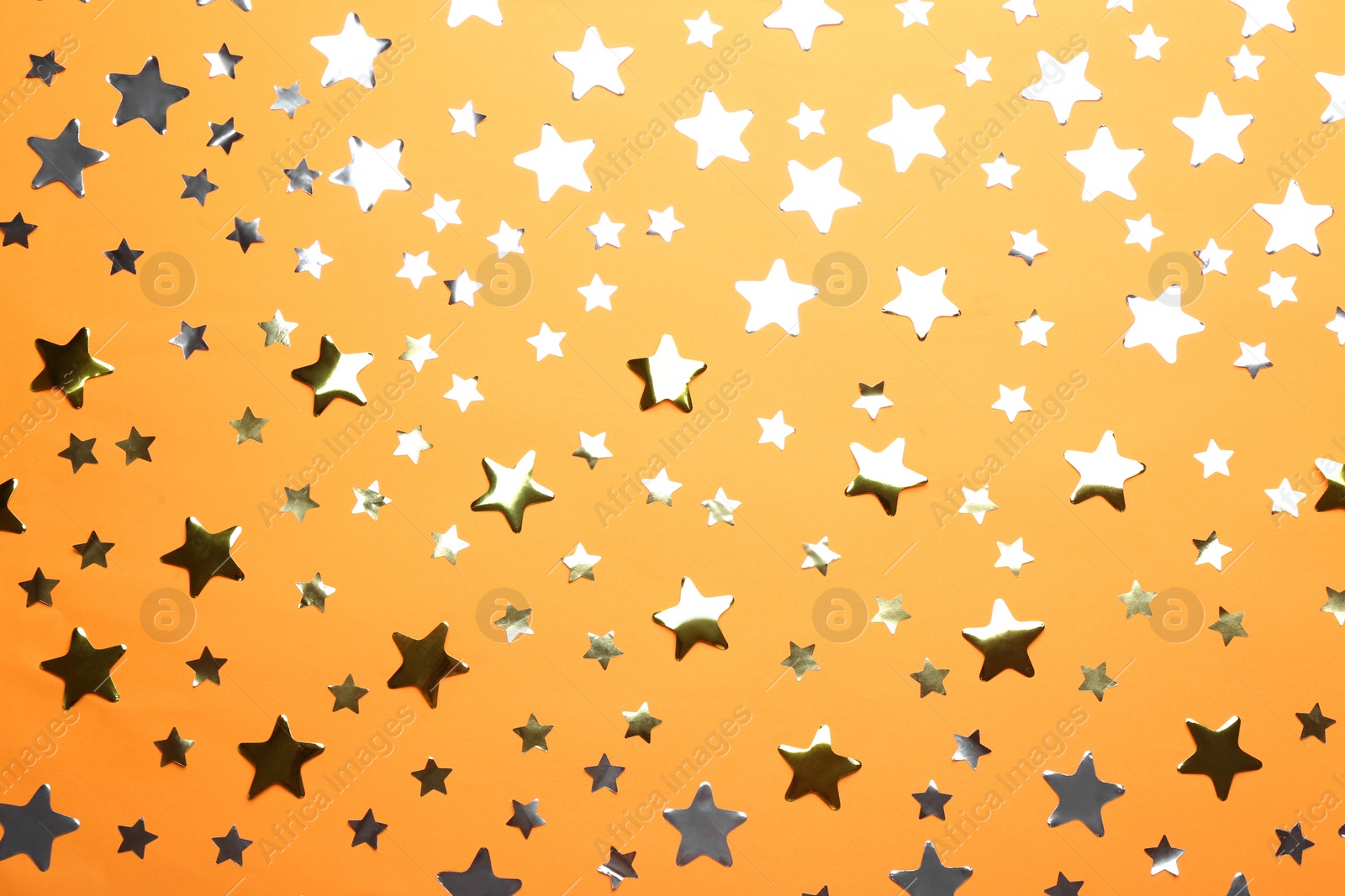 Photo of Confetti stars on orange background, flat lay. Christmas celebration