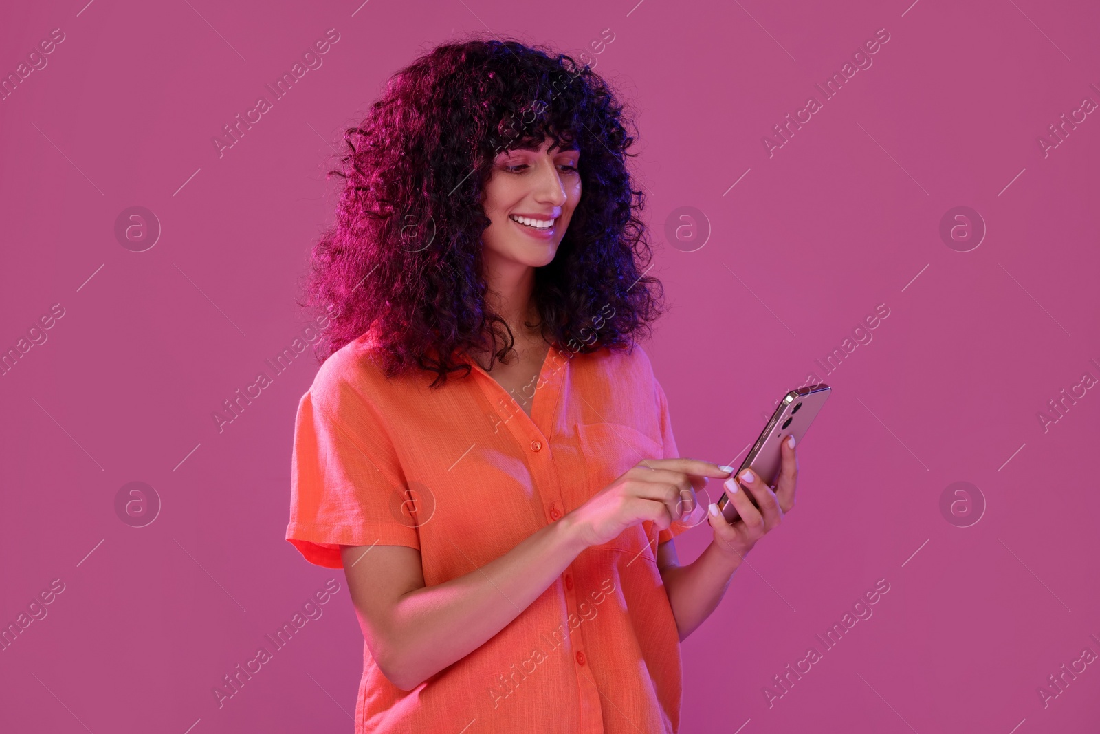 Photo of Woman sending message via smartphone on pink background