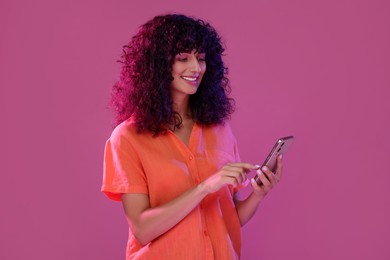 Woman sending message via smartphone on pink background