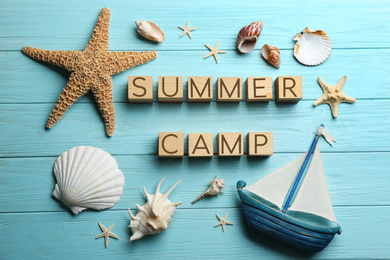 Photo of Flat lay composition with phrase SUMMER CAMP made of cubes on light blue wooden background