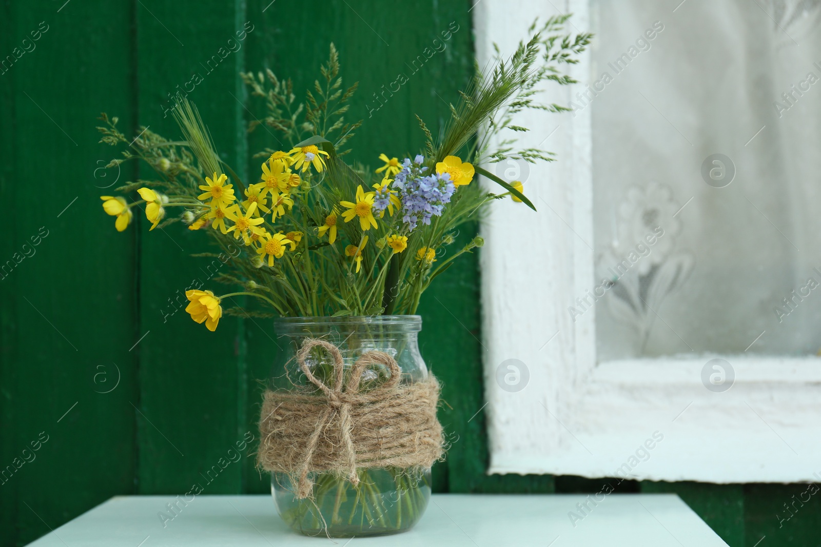 Photo of Bouquet of beautiful wildflowers in glass vase on table near window outdoors