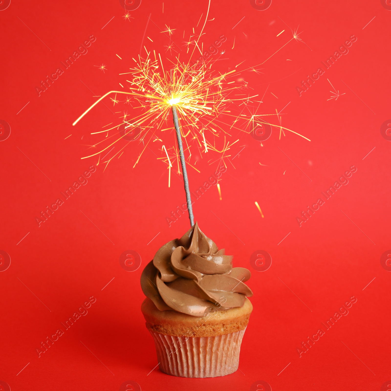 Image of Birthday cupcake with sparkler on red background