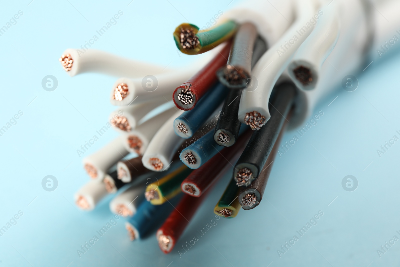 Photo of Many electrical wires on light blue background, closeup