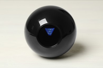 Photo of Magic eight ball with prediction Looks Like Yes on white table