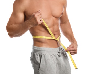 Photo of Young man with slim body using measuring tape on white background, closeup view