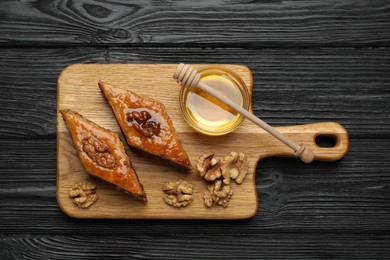 Delicious sweet baklava with walnuts and honey on black wooden table, top view