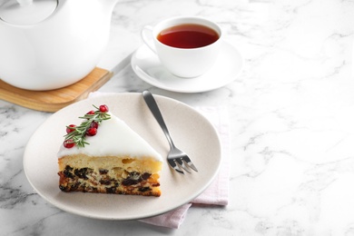 Slice of traditional Christmas cake decorated with rosemary and pomegranate seeds served on white marble table, space for text