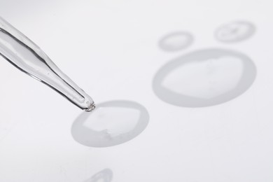 Glass pipette and transparent liquid on white background, closeup