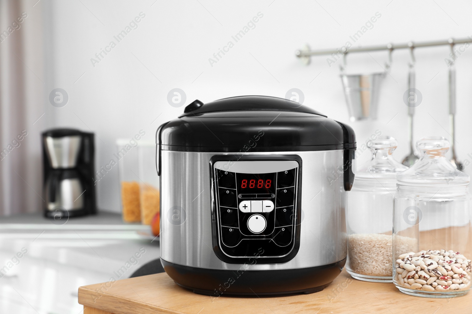Photo of Jars with rice and beans near modern multi cooker on table in kitchen