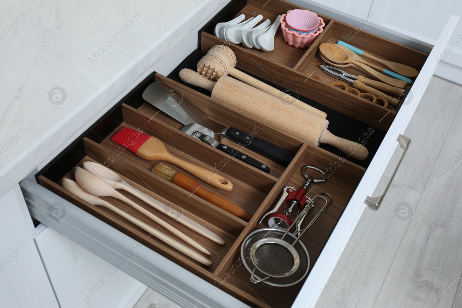 Photo of Open drawer with utensil set indoors. Order in kitchen