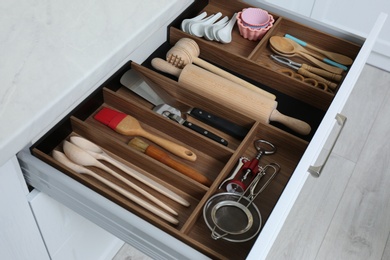 Open drawer with utensil set indoors. Order in kitchen