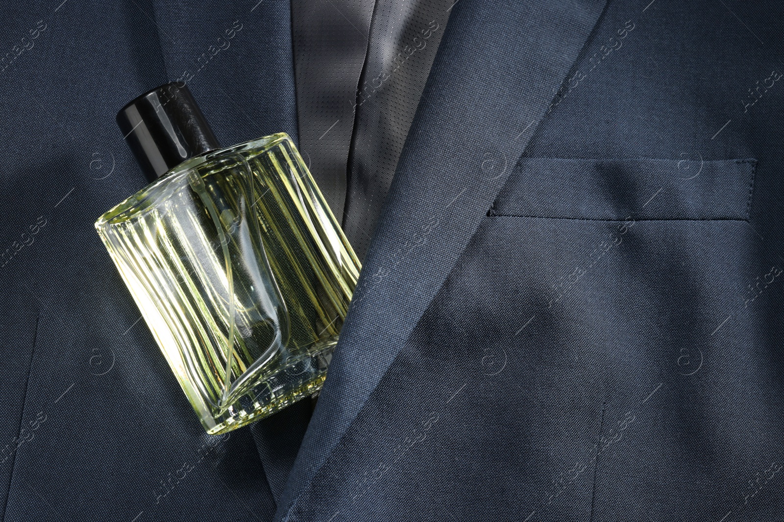 Photo of Luxury men's perfume in bottle on grey jacket, top view. Space for text