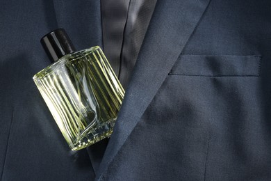 Luxury men's perfume in bottle on grey jacket, top view. Space for text