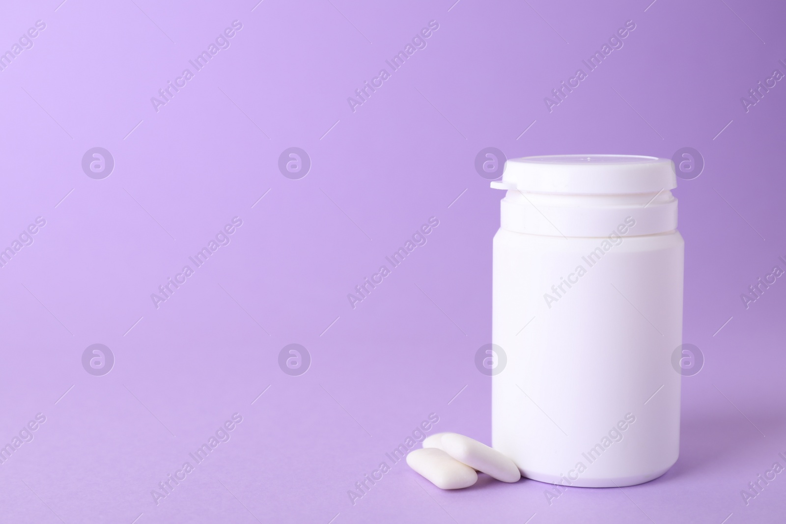 Photo of Jar with chewing gums on lilac background. Space for text