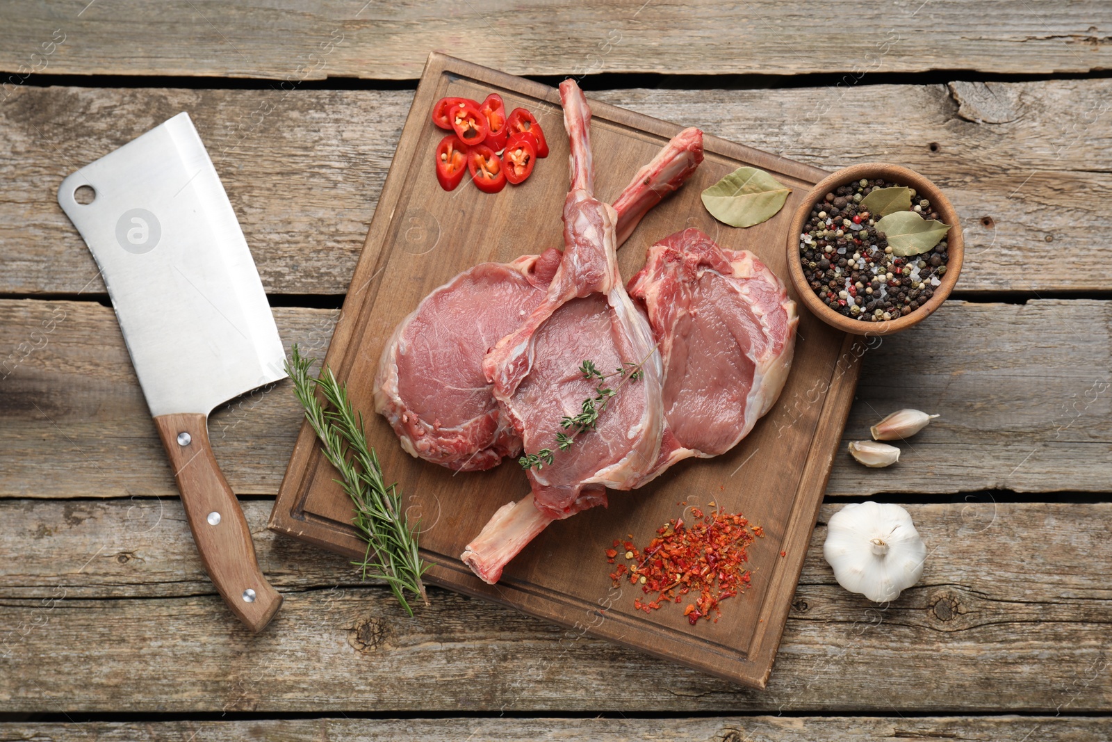 Photo of Fresh tomahawk beef cuts, butcher knife and spices on wooden table, top view