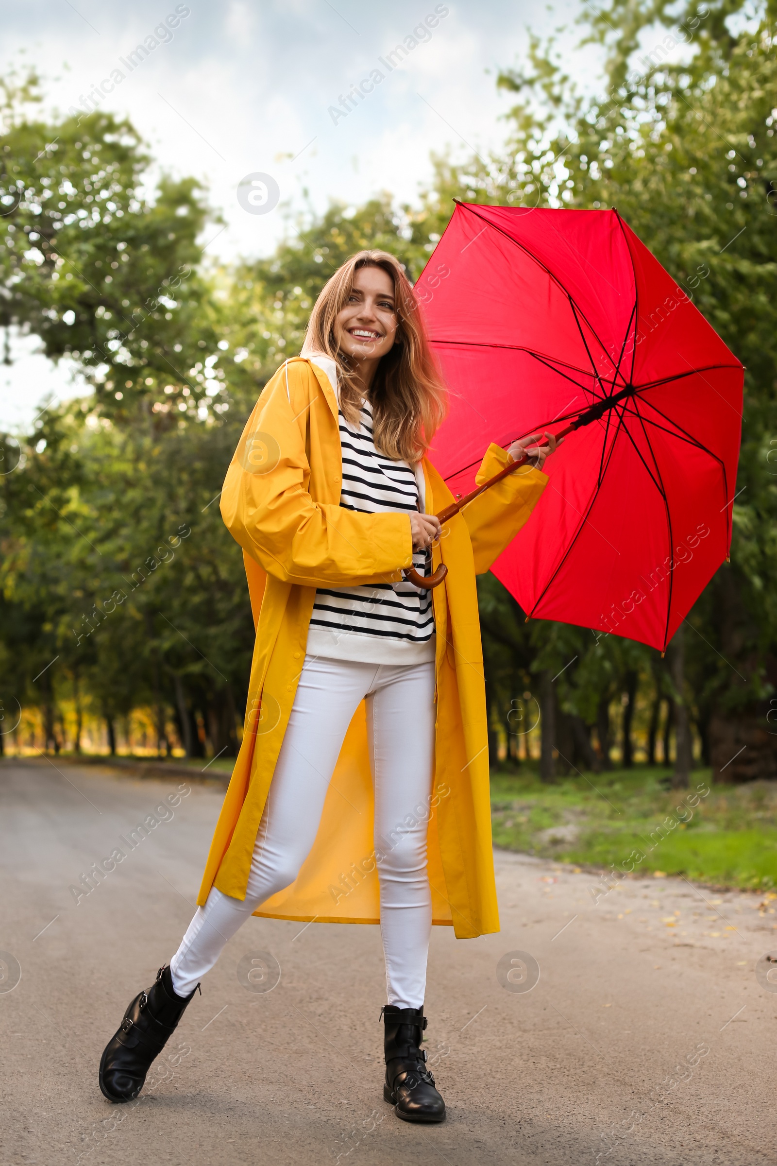 Photo of Beautiful young woman wearing stylish autumn clothes with red umbrella in park