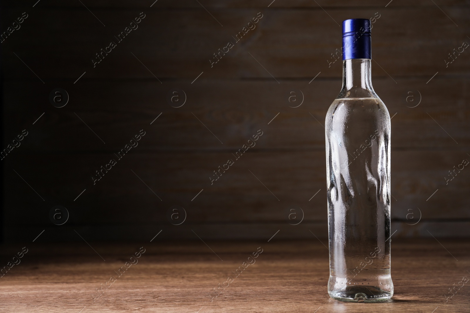 Photo of Bottle of vodka on table against wooden background. Space for text