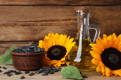 Sunflower cooking oil, seeds and yellow flowers on wooden table